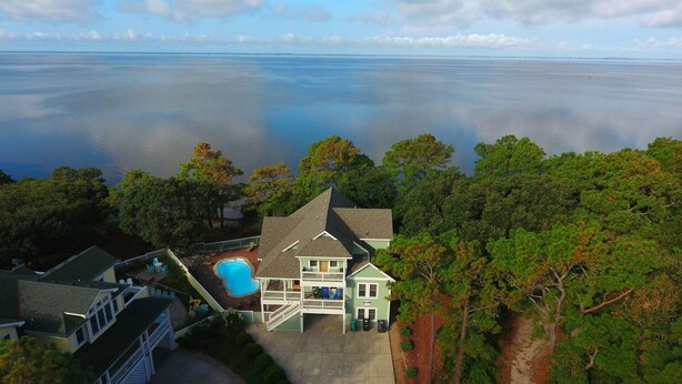 A house with a swimming pool, surrounded by trees and overlooking a large body of water. - Soundfront, Sound views! Private Pool, Community Amenities, 504, Lost N' Sound (Corolla)