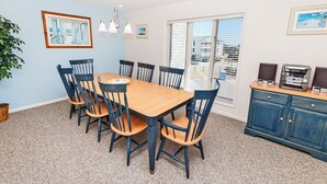 A dining area with a wooden table and chairs, a blue cabinet with speakers, and a window with blinds. - Oceanside, close to beach, Community Pools, Community Tennis, 643, Ocean Dream (Corolla)