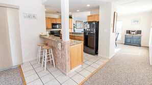 A modern kitchen with a central island, wooden cabinets, and a stainless steel refrigerator. - Oceanside, close to beach, Community Pools, Community Tennis, 643, Ocean Dream (Corolla)