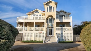 A large, multi-story building with a central tower, multiple balconies, and a gated entrance. - Oceanside, Private Pool, Rec Room, Vllyball, PI157, Vintage Pine (Corolla)