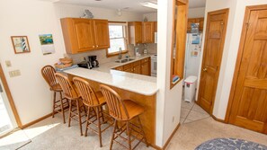A kitchen with wooden cabinets, a marble countertop, and a bar stool area.