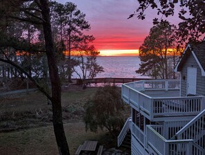 A wooden deck with a staircase leading to a cabin overlooking a sunset over the water. - Semi-Soundfront, Rec Room, Community Amenities, 533,Sound Secret (Corolla)