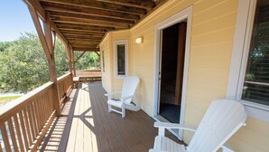 Une terrasse en bois avec deux chaises Adirondack blanches et un espace porche abrité.