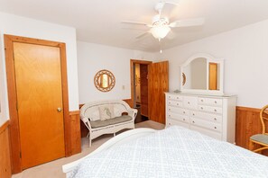 Une chambre à coucher avec un lit, une commode et un ventilateur de plafond.
