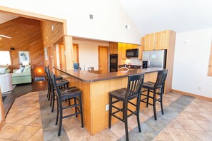 A modern kitchen with a central island, wooden cabinets, and a stainless steel refrigerator.