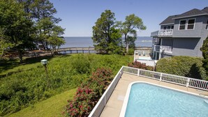 A residential property with a swimming pool, a wooden deck, and a view of the sea.