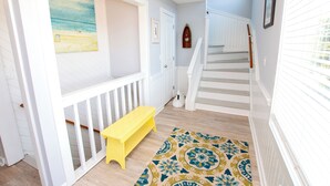 A hallway with a staircase, a bench, a patterned rug, and a painting on the wall. - Oceanside, Pool, Hot Tub, 945 ft to Beach Access, WW935, Sea Watch (Corolla)