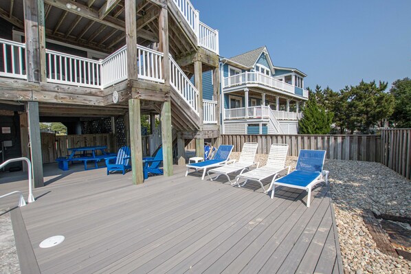 A wooden deck with lounge chairs and a picnic table.