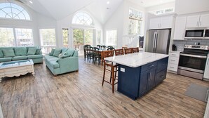 A spacious kitchen with a central island, wooden flooring, and white cabinetry. - Oceanside, Private Pool, Hot Tub, Pool Table, Dogs Welcome, WC1084, Oaks Beach Oasis (Corolla)