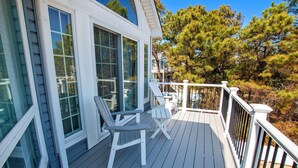 A wooden deck with two Adirondack chairs and a small table, overlooking a forested area. - Oceanside, Private Pool, Hot Tub, Pool Table, Dogs Welcome, WC1084, Oaks Beach Oasis (Corolla)