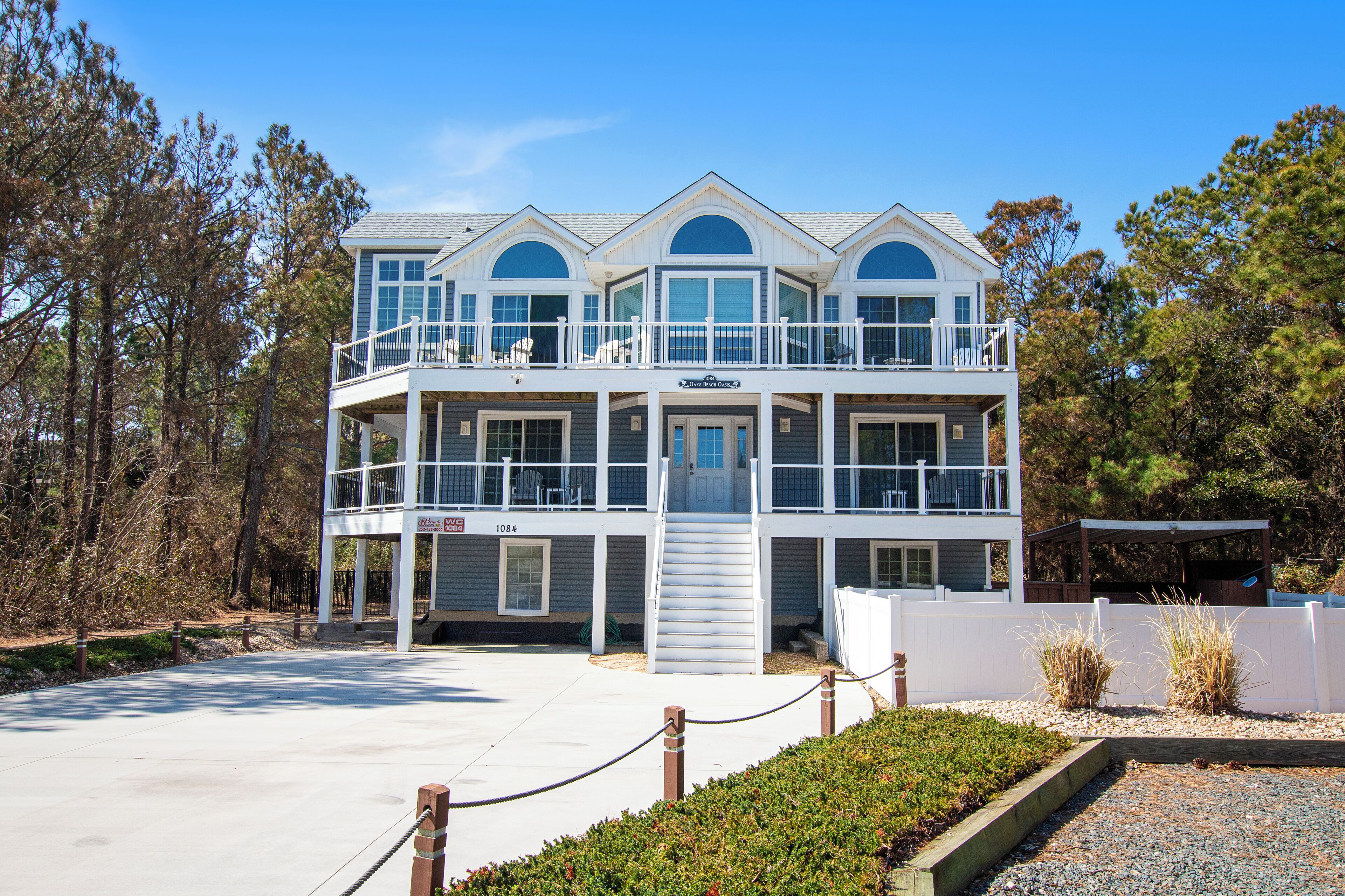 A multi-story building with balconies, a covered patio, and a view of the surrounding trees.