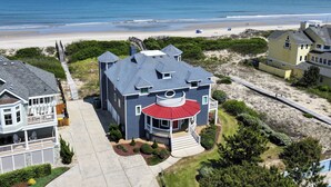 Ein großes Haus mit breiter Veranda, einer Terrassenvorderseite und Blick auf den Strand.
