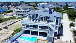 Ein mehrstöckiges Strandhaus mit Pool, Balkonen und einer Terrassenanlage.