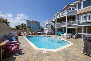 A pool area with lounge chairs and a hot tub.