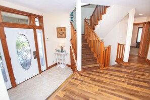 A wooden staircase with a handrail, a white door with a glass panel, and a small table with a lamp. - OCEANFRONT, Ocean Views, Priv Pool, H Tub!, BU38, Chunk O Dune (Corolla)