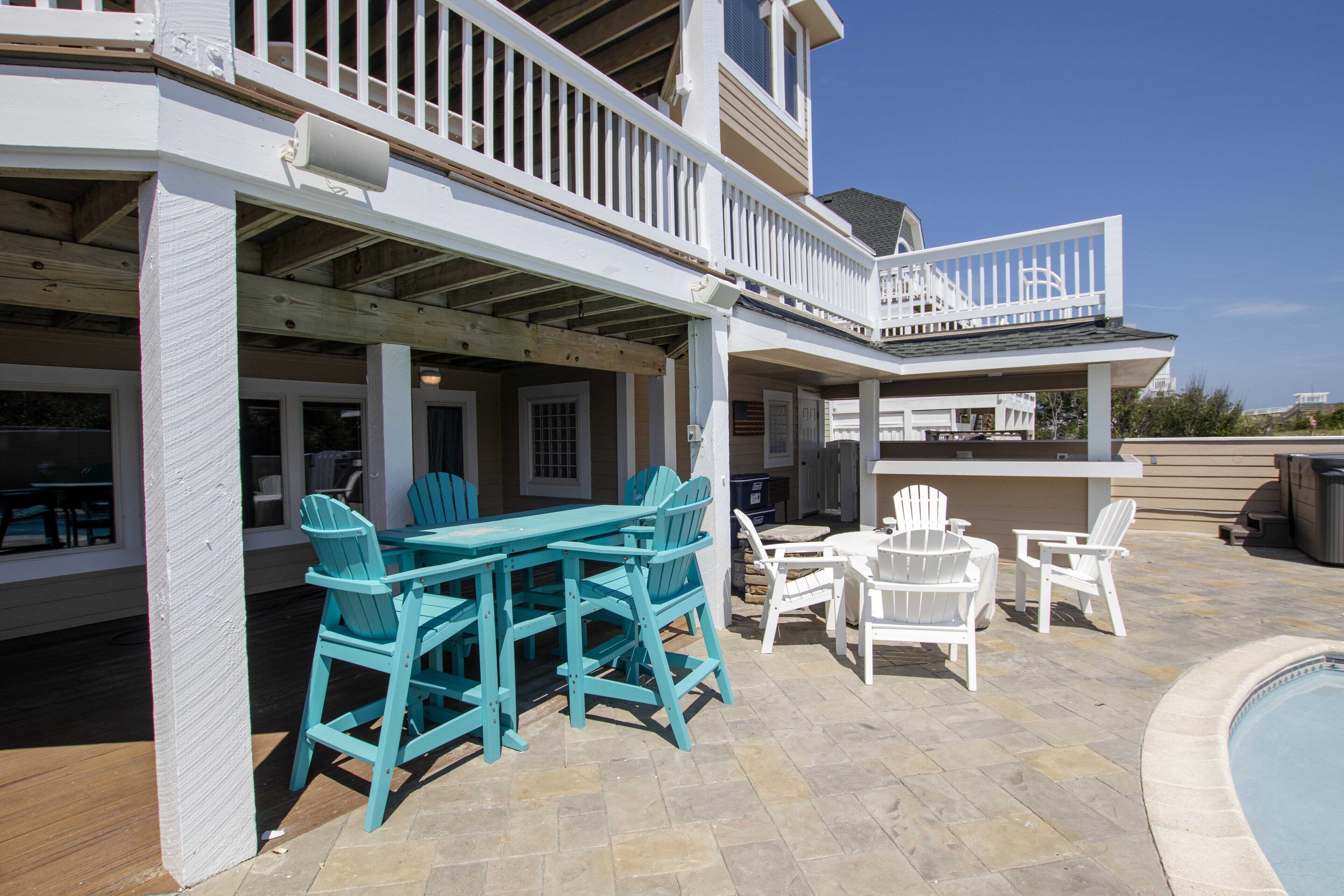 A covered outdoor patio with a pool, seating area, and a second-story balcony.