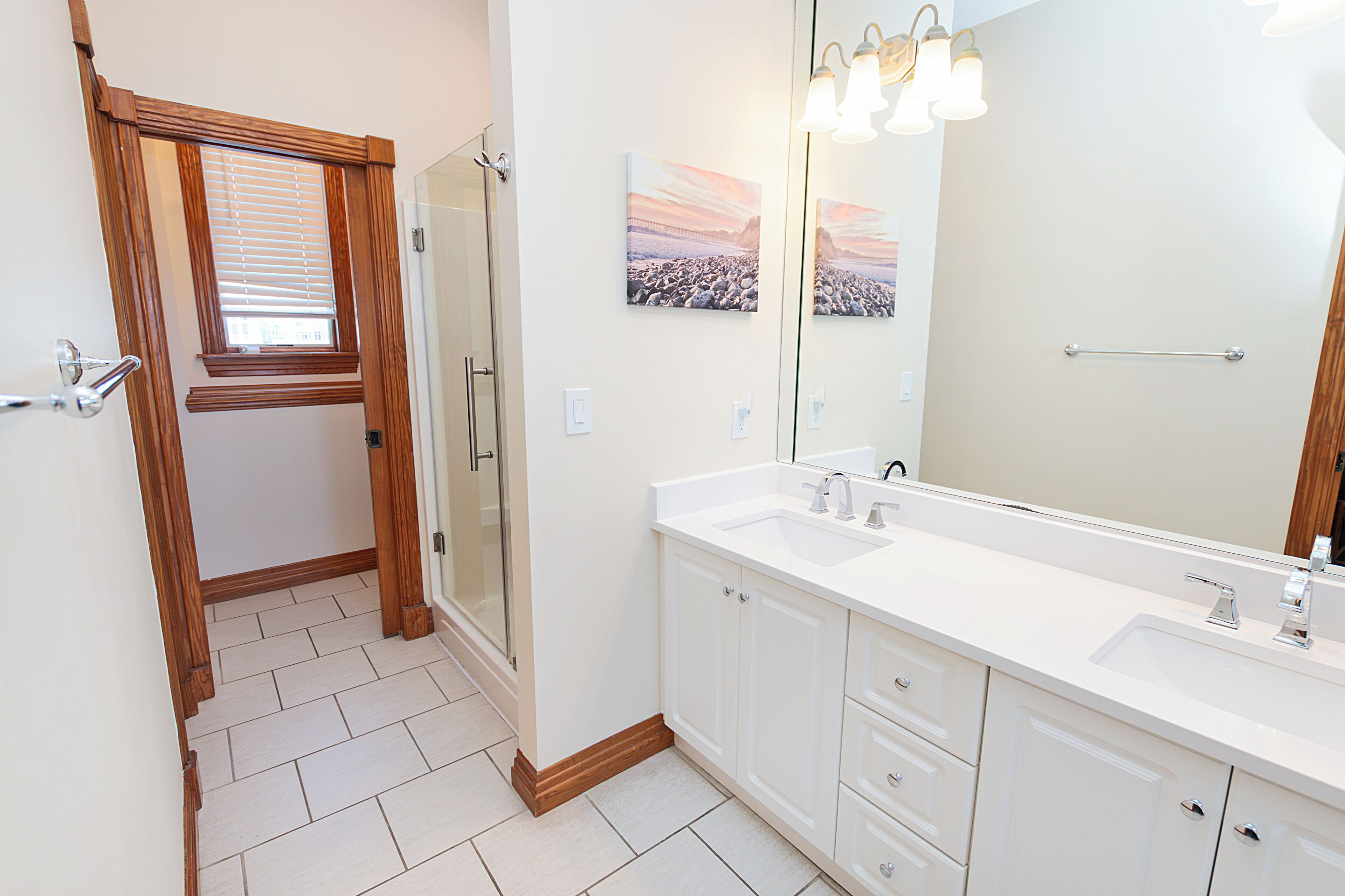 A modern bathroom with a walk-in shower, a large mirror, and a double sink vanity.