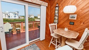 A wooden-paneled room with a sliding glass door to a deck, a small table with chairs, and a wall-mounted light fixture. - Oceanside, Close to beach, Sunroom, Carport, SNH351, Sea Sharp (Nags Head)