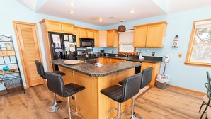 A kitchen with wooden cabinets, a granite countertop, and a central island with bar stools. - Soundfront, Priv Dock, Sound Views, Sun Deck, SA425, Sound Mind (Duck)