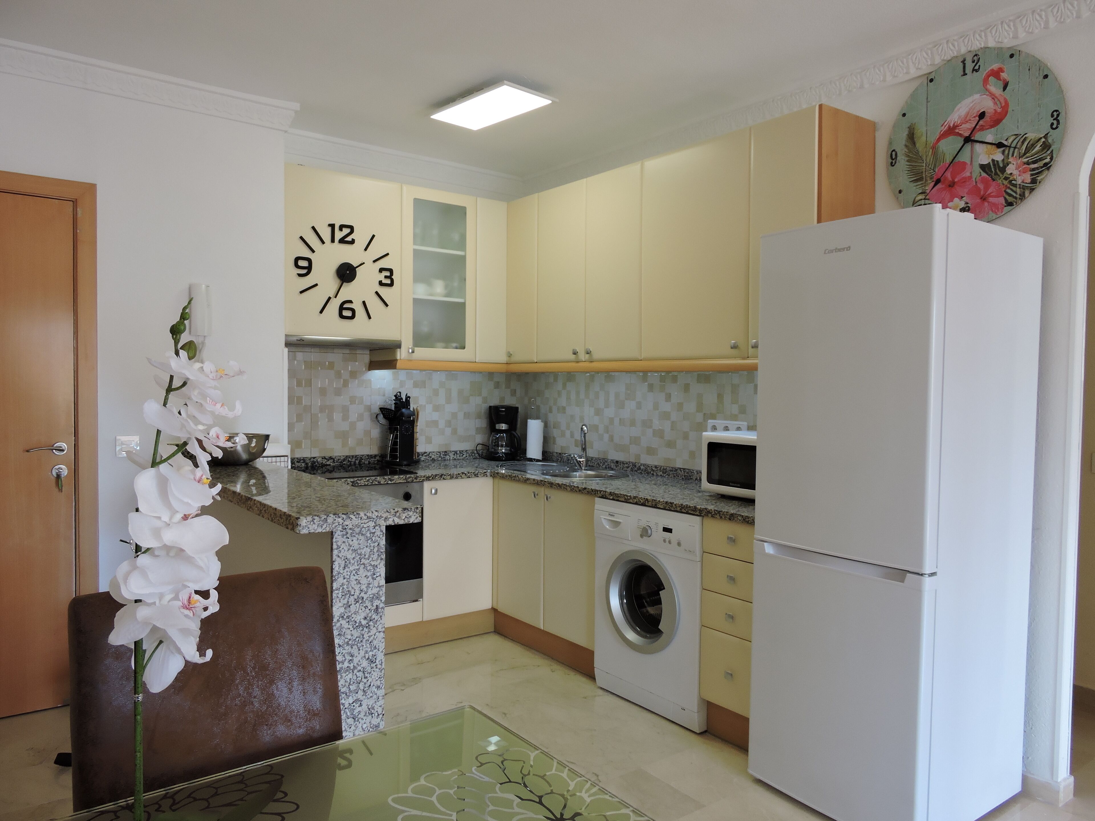 A compact kitchen with a microwave, coffee maker, and washing machine.