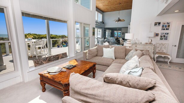 A spacious living room with a large sectional sofa, a wooden coffee table, and a view of the ocean through large windows. - OCEANFRONT, Private Pool, Ocean Views, Beach Walkway, Hot Tub, WL1035, PiraSea (Corolla)