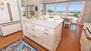 A kitchen with a large island, white cabinets, and a view of the ocean. - OCEANFRONT, Private Pool, Ocean Views, Beach Walkway, Hot Tub, WL1035, PiraSea (Corolla)