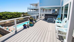 A deck with a pool, lounge chairs, and potted plants. - OCEANFRONT, Private Pool, Ocean Views, Beach Walkway, Hot Tub, WL1035, PiraSea (Corolla)