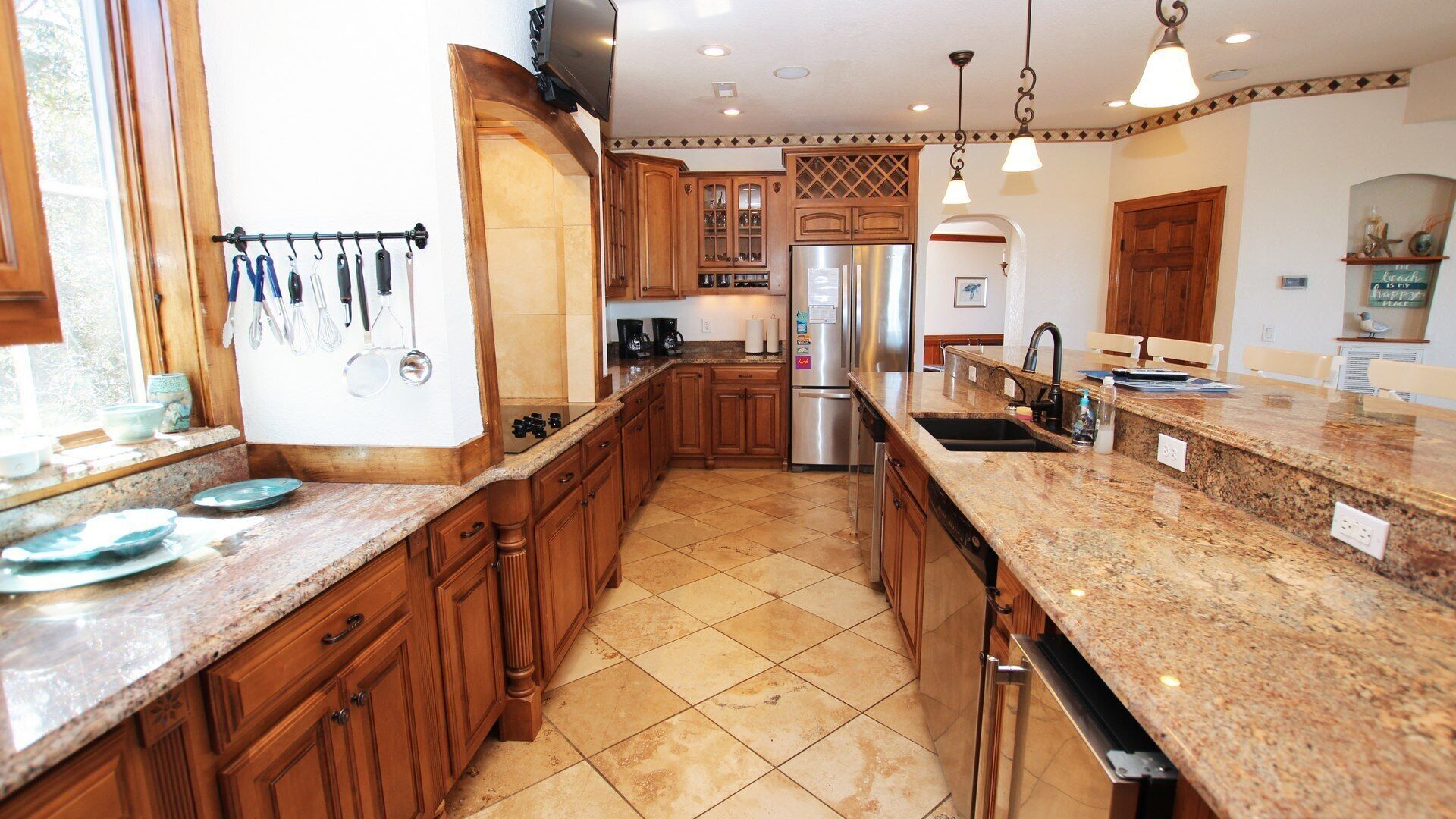A kitchen with wooden cabinets, granite countertops, stainless steel appliances, and pendant lighting.