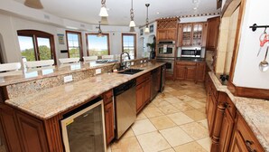 A spacious kitchen with granite countertops, wooden cabinets, and stainless steel appliances. - Soundside, Priv Pool, H Tub, ELEV, Rec Rm, Theatr Rm, FR1, The Drake (Duck)