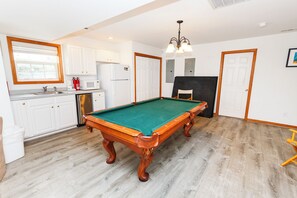 A pool table in a room with a kitchen area, a door, and a ceiling light fixture. - Semi-Oceanfront, 7 BRs, Priv Pool, H Tub, Rec Rm, WL1068, Footloose (Corolla)