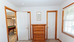 A bedroom with two beds, a dresser, and a framed picture on the wall.
