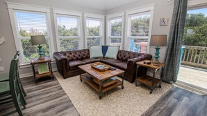 A cozy living room with a brown leather sofa, a wooden coffee table, and a patterned rug. - Oceanside, 4 BRs, Private Pool, Hot Tub, Screened Porch, WC955, La Carolina (Corolla)