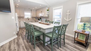 A kitchen with a central island, white cabinets, and green chairs. - Oceanside, 4 BRs, Private Pool, Hot Tub, Screened Porch, WC955, La Carolina (Corolla)