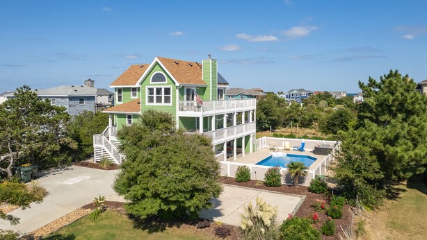 A two-story house with a balcony, a swimming pool, and a well-maintained garden.