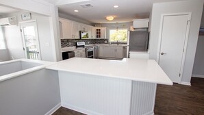 A modern kitchen with white cabinetry, a central island, and a view of the outdoors. - Semi-Oceanfront, Private Pool with Cabana! Ocean Views! Pool Table, 126, Newmania (Corolla)