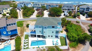 A large two-story house with a swimming pool and multiple decks, surrounded by other houses and a beach view. - Semi-Oceanfront, Private Pool with Cabana! Ocean Views! Pool Table, 126, Newmania (Corolla)