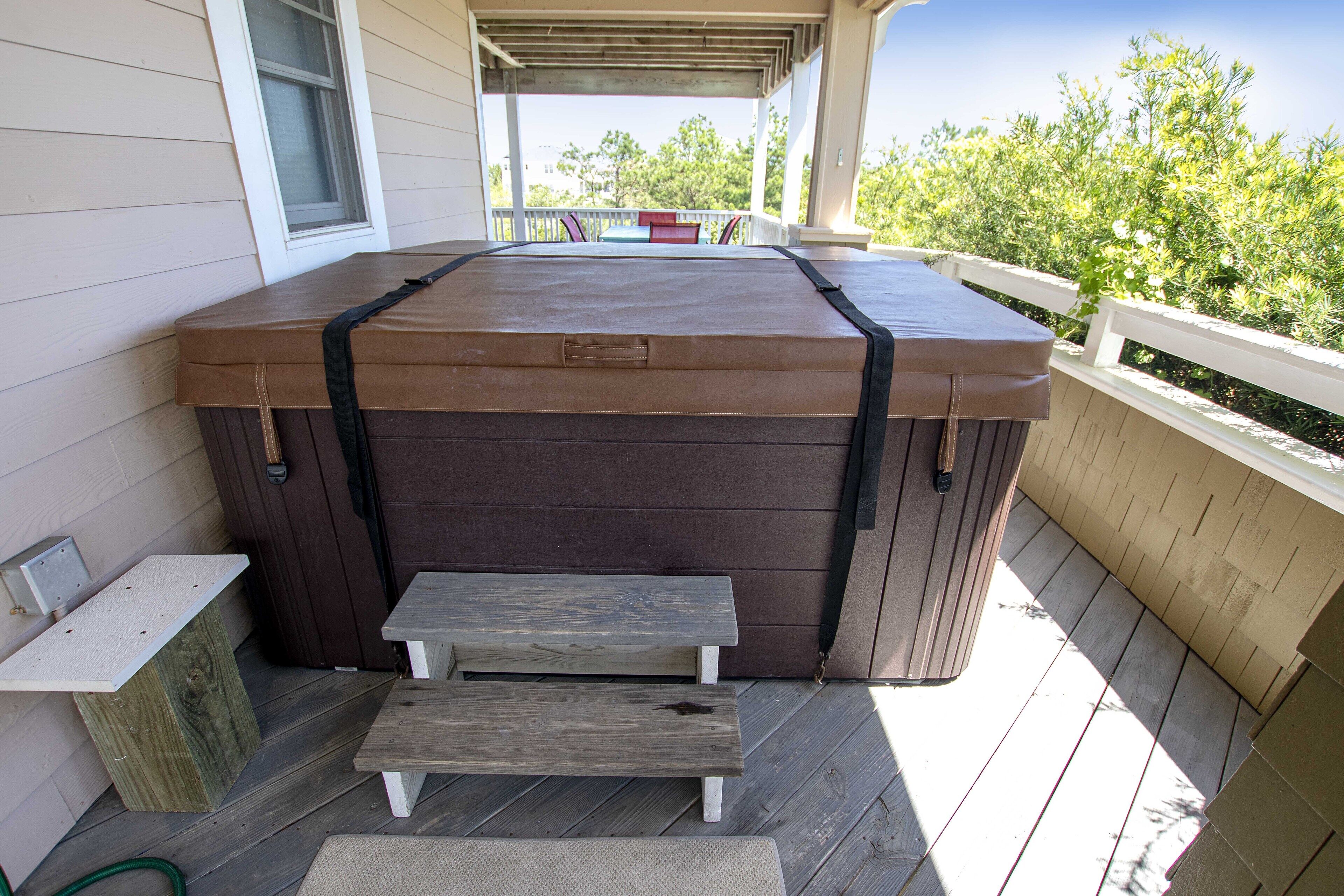 A hot tub on a wooden deck with a bench and a small table.