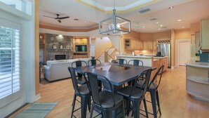 A spacious kitchen with a dining area, a stone fireplace, and a modern ceiling fan.
