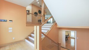 A spacious living area with a wooden staircase and a glass railing.