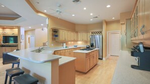 A spacious kitchen with a large island, wooden cabinets, and modern appliances.