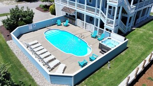 A multi-story building with a swimming pool, outdoor seating, and a hot tub.