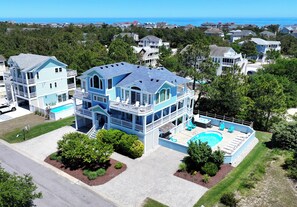 A large two-story house with a swimming pool, surrounded by trees and a view of the ocean. - Oceanside, Private Pool, ELEV, Hot Tub, Corolla Light Amenities, BH6, Sunny Rays (Corolla)