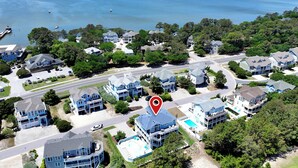 An aerial view of a coastal residential area with houses, a road, and a body of water.