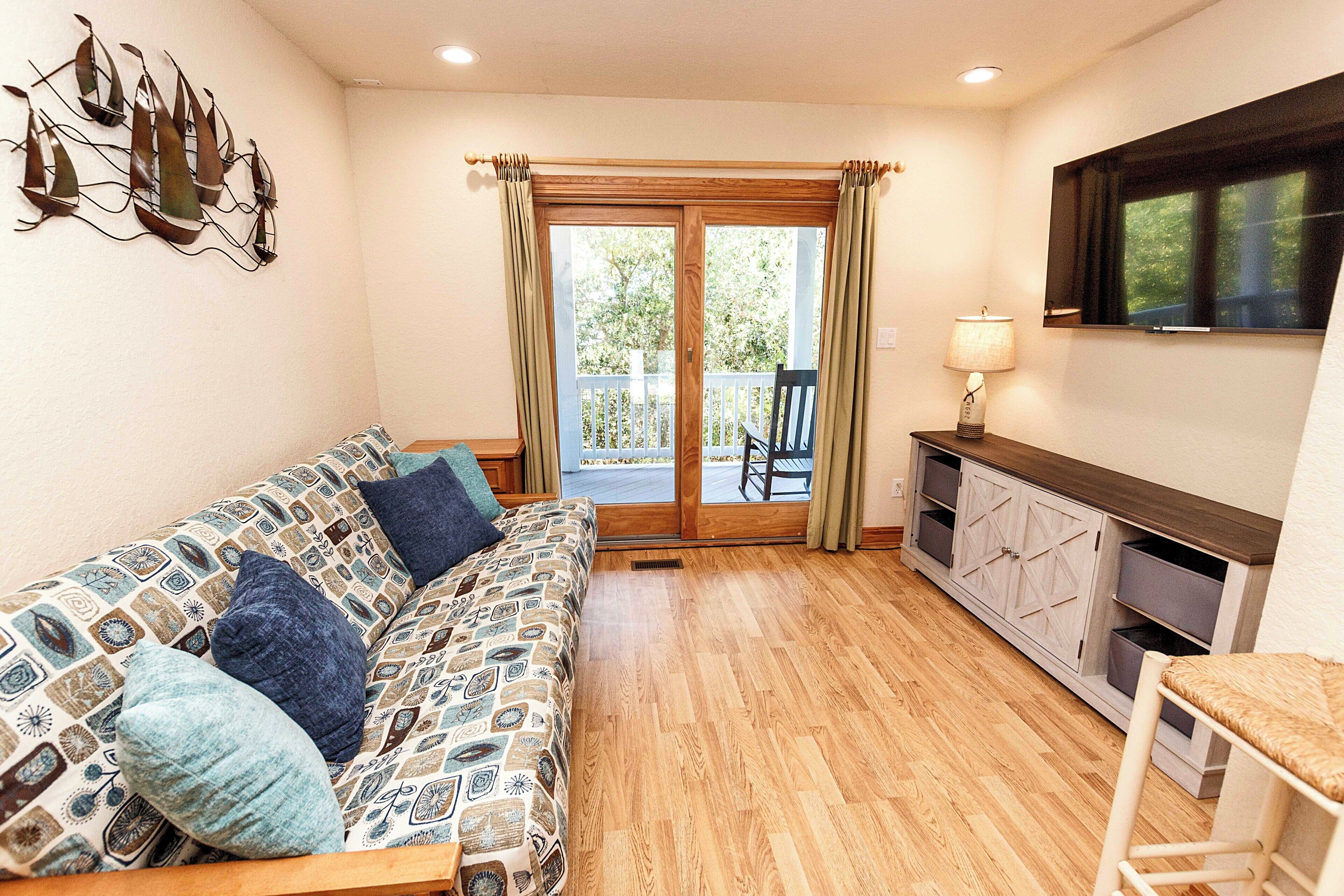 A cozy living room with a patterned sofa, a wooden cabinet, and a dining area with a chair.