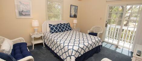 A bedroom with a large bed, two nightstands, a chair, and a window with blinds.