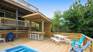 A wooden deck with a pool, outdoor seating, and a covered area. - Oceanside, Pool, Hot Tub, Rec Rm, WC1005, Happily Ours (Corolla)