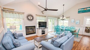 A living room with a fireplace, sofa, television, and teal chairs. - Oceanside, Pool, Hot Tub, Rec Rm, WC1005, Happily Ours (Corolla)