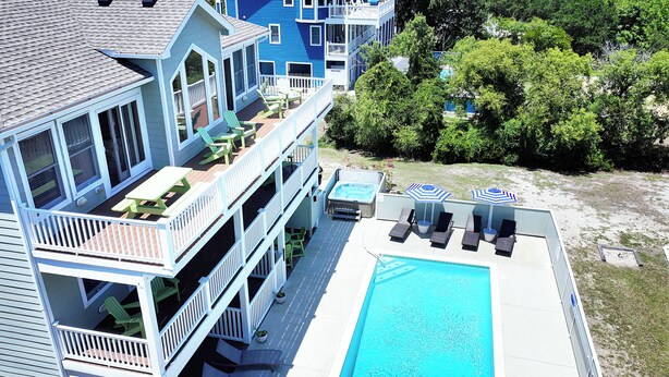 A multi-story building with a swimming pool, outdoor seating, and a deck.