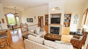 A spacious living room with a large sectional sofa, a fireplace, a television, and a dining area with a wooden table and chairs.