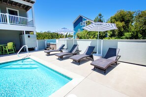 A swimming pool with lounge chairs and umbrellas, a covered patio area, and a two-story building with a balcony. - Oceanside, Prv Pool, H Tub, Rec Rm, Sun Decks, WC887, Ashley's Nest (Corolla)